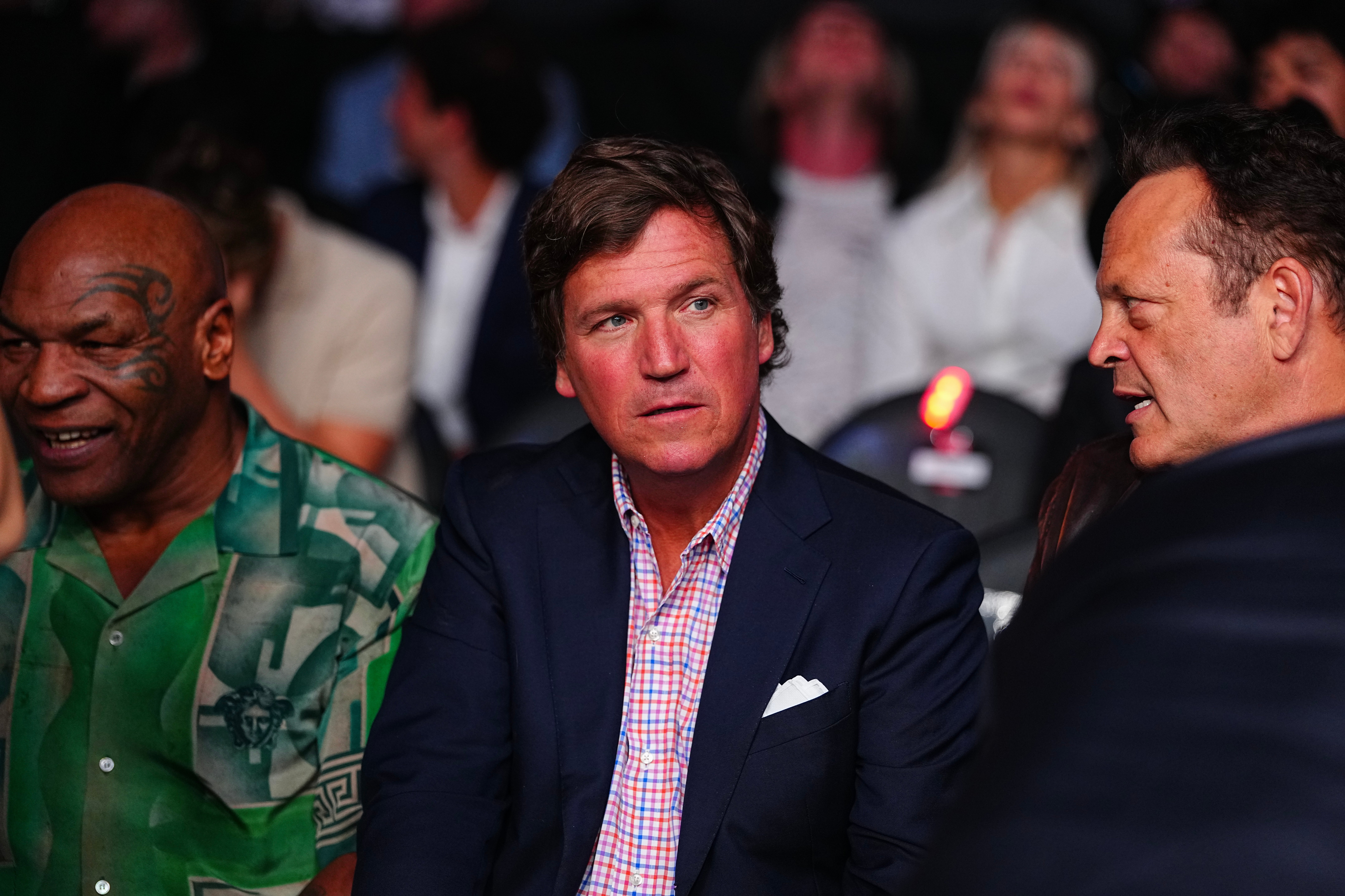 Tucker Carlson sits between Mike Tyson and a talking Vince Vaughn at a UFC fight