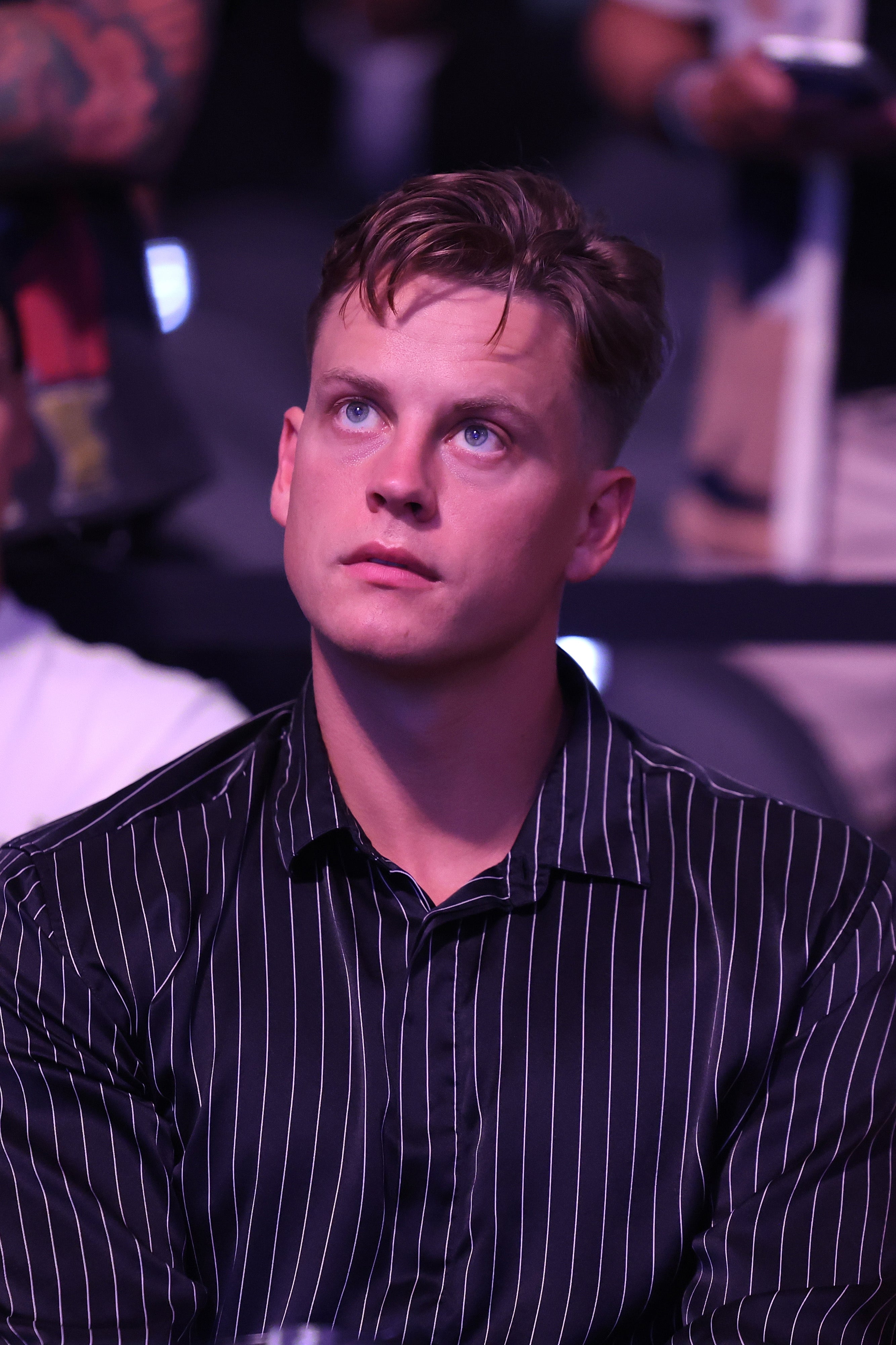 Joe Burrow in a striped shirt looking upwards at a UFC fight