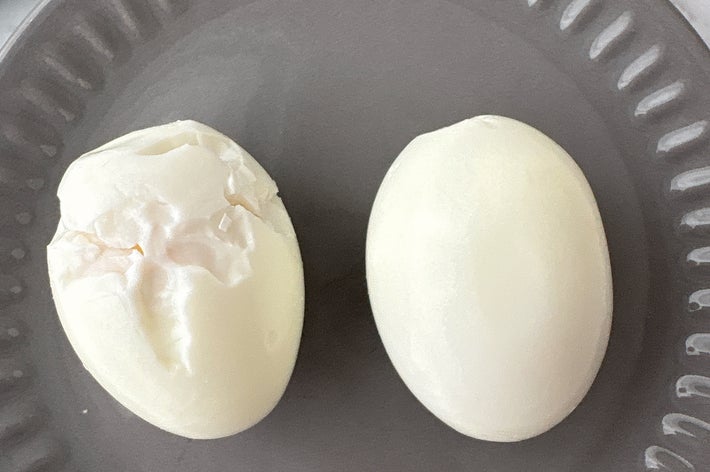 2つのゆで卵が灰色の皿に置かれている。片方は殻がむかれている。