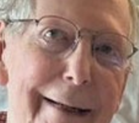 Elderly person with glasses smiling at the camera
