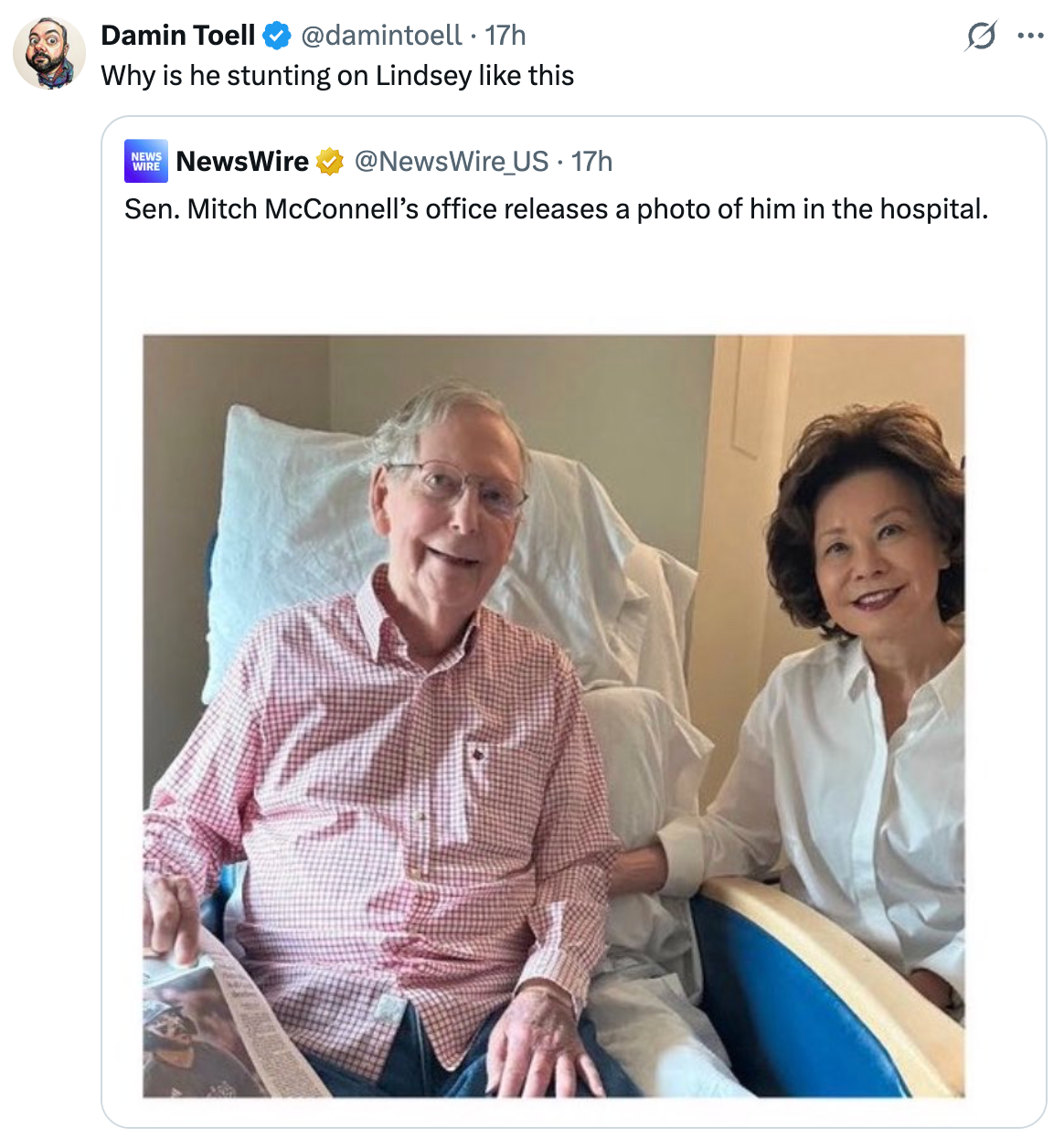 A man, seated in a hospital bed, is accompanied by a smiling woman. They hold hands, suggesting a supportive visit