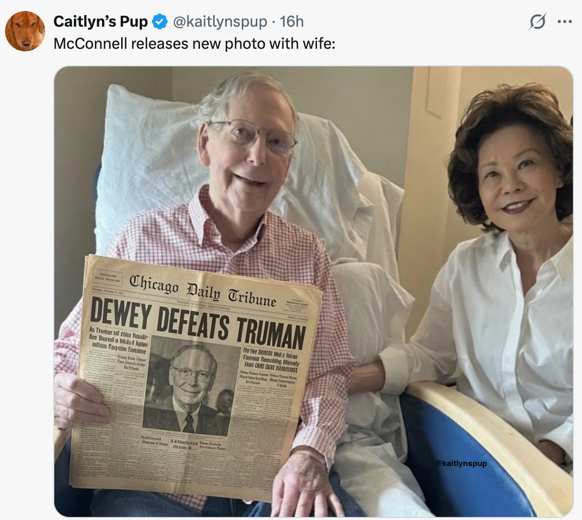 A couple smiles while the man holds a historic "Dewey Defeats Truman" newspaper. They appear relaxed and happy
