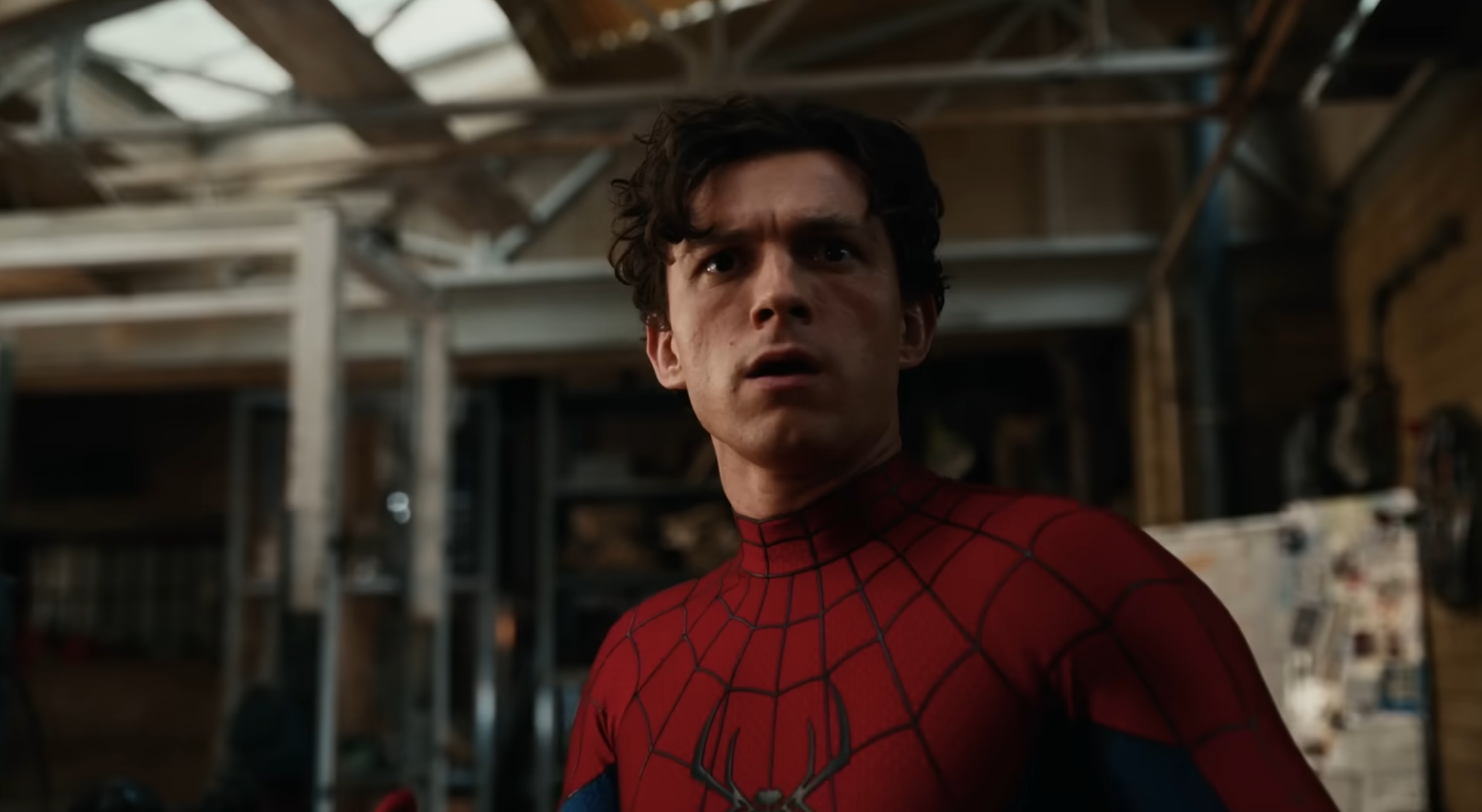 Tom Holland in a Spider-Man costume looks surprised in an industrial setting