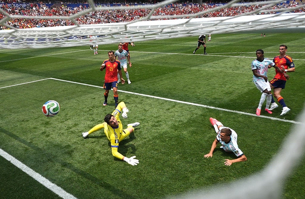 Fotballkamp med spillere i bevegelse nær målet, en keeper midt i redningen og et fullsatt stadion i bakgrunnen