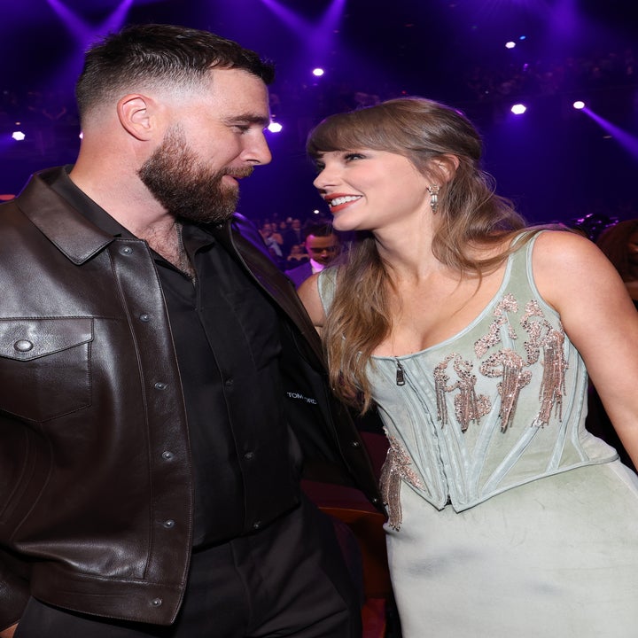 Two people smiling at each other at an event. One wears a leather jacket, the other a stylish dress
