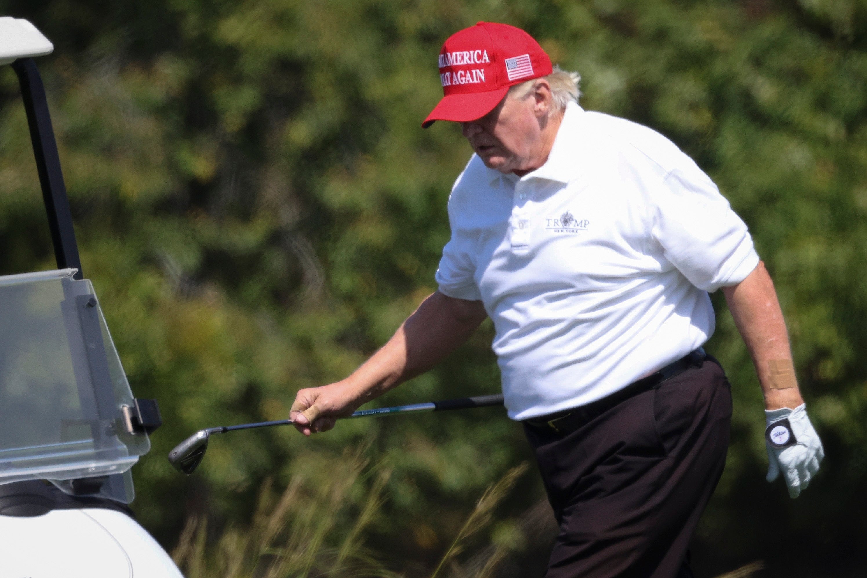 Person som har på seg en "Make America Great Again" hatt, golf i hvit poloskjorte, gå på en golfbane