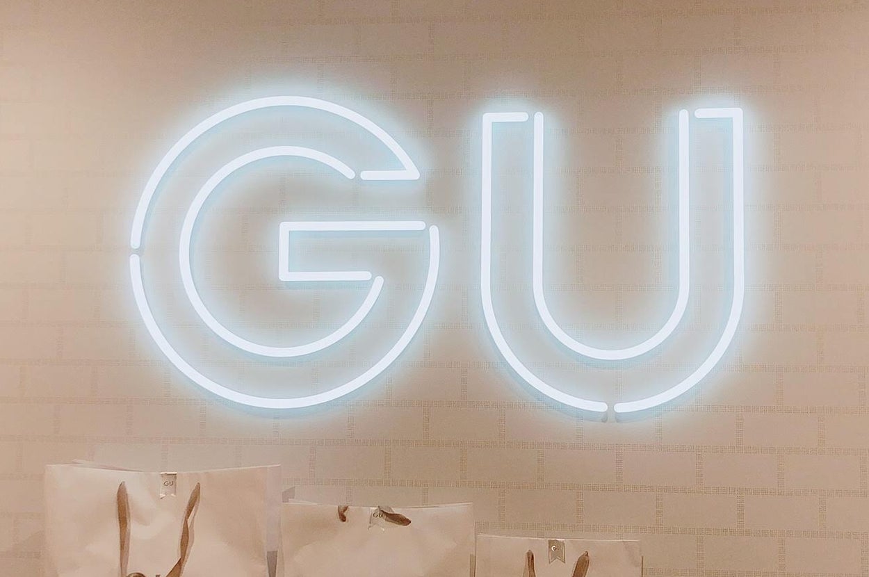 GUストアの壁にあるネオンサインと、ギフトラッピングサービスを案内するショッピングバッグ。