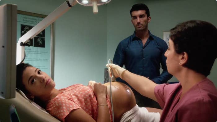 A large   pistillate   lies connected  a aesculapian  exam array  during an ultrasound, with a antheral   and caregiver  looking on