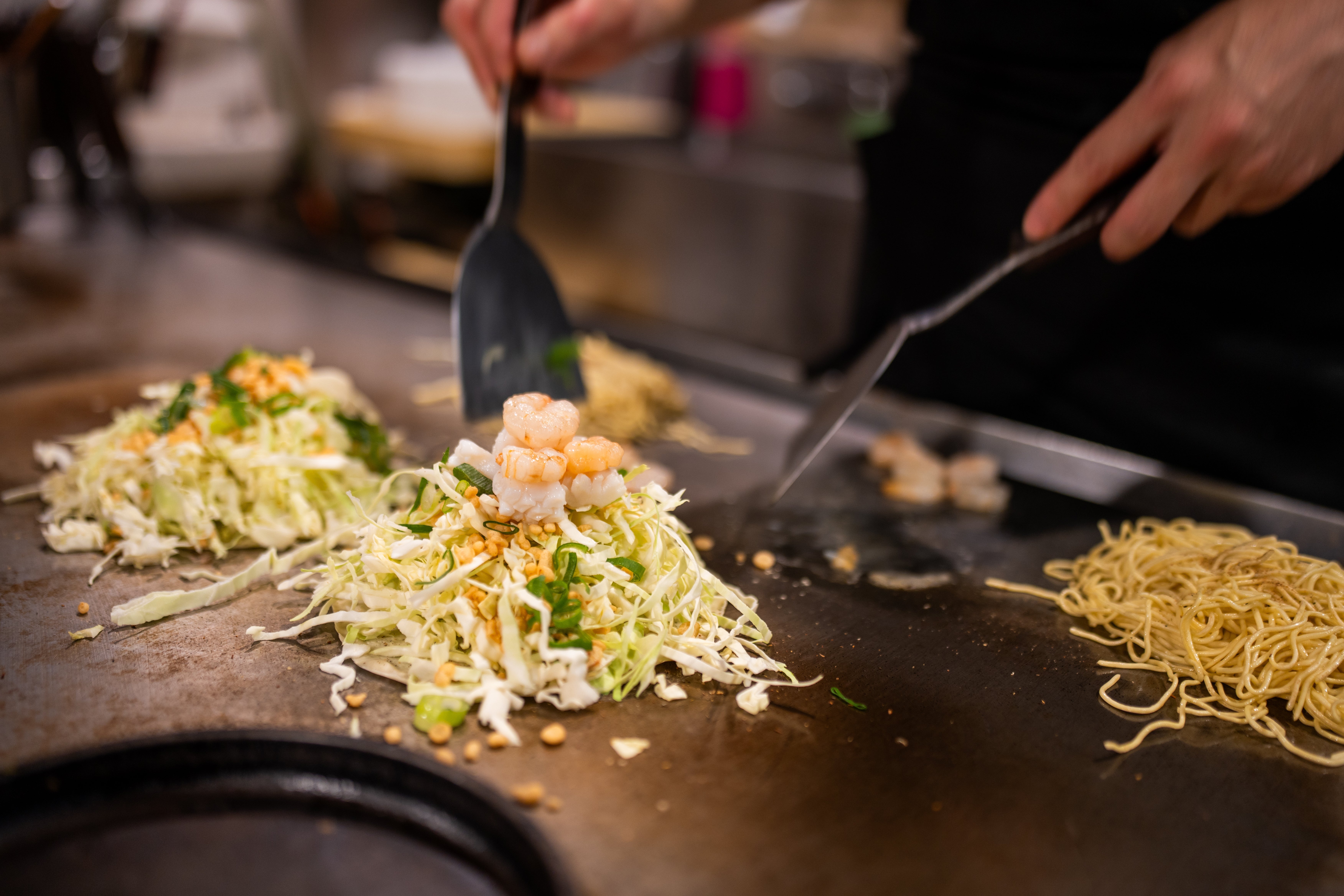 En hibachi-kokk lager sjømat og grønnsaker på en grill
