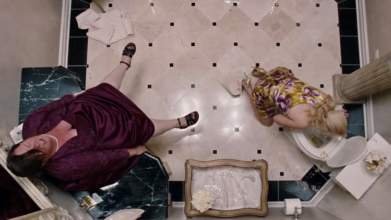 Melissa McCarthy bæser i en vask mens Wendi McLendon-Covey spyr på et toalett i Bridesmaids