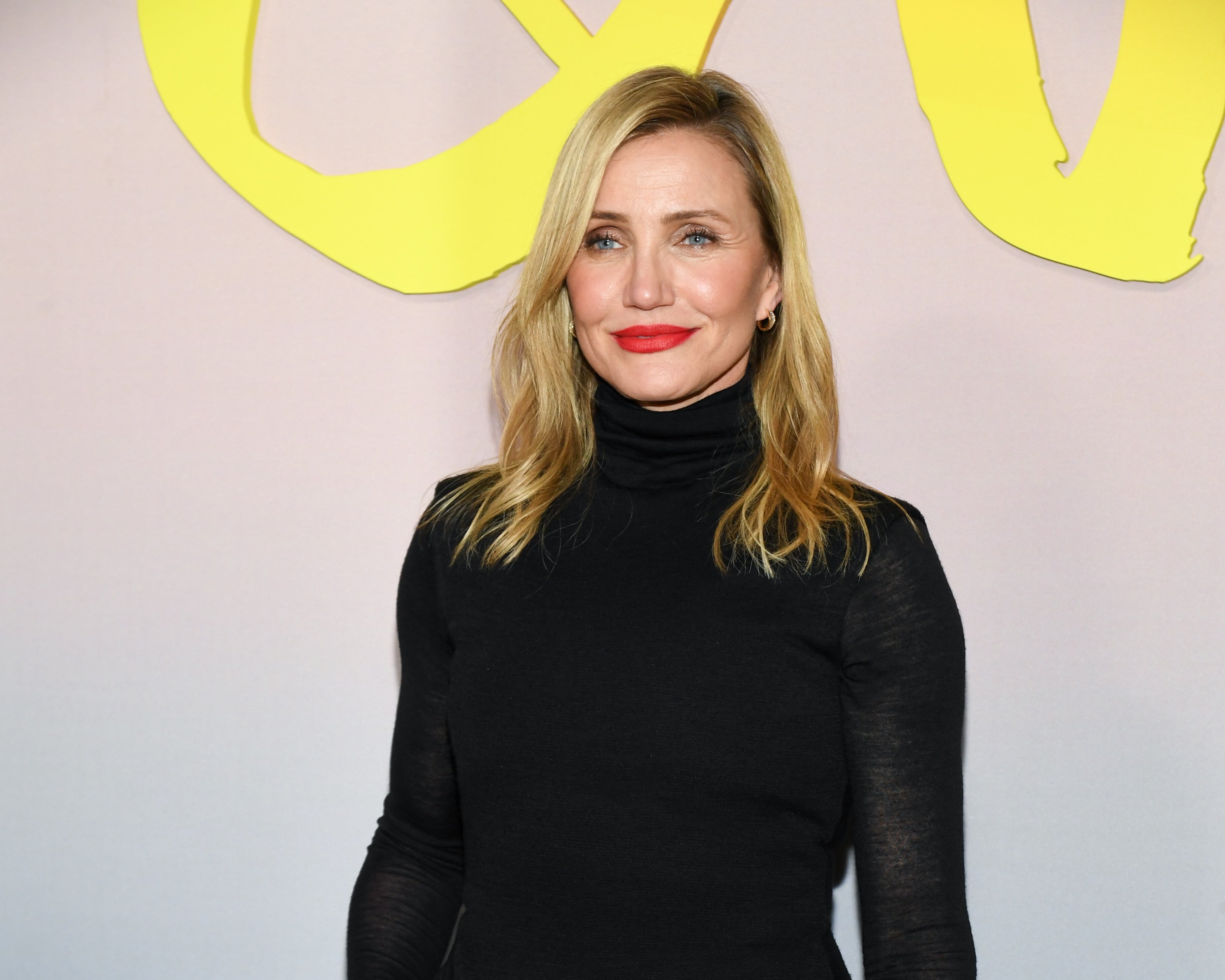 Woman in a black turtleneck dress smiles, posing at an event
