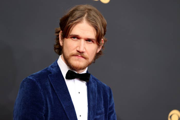 Man in a velvet suit and bow tie on a formal event red carpet, looking to the side