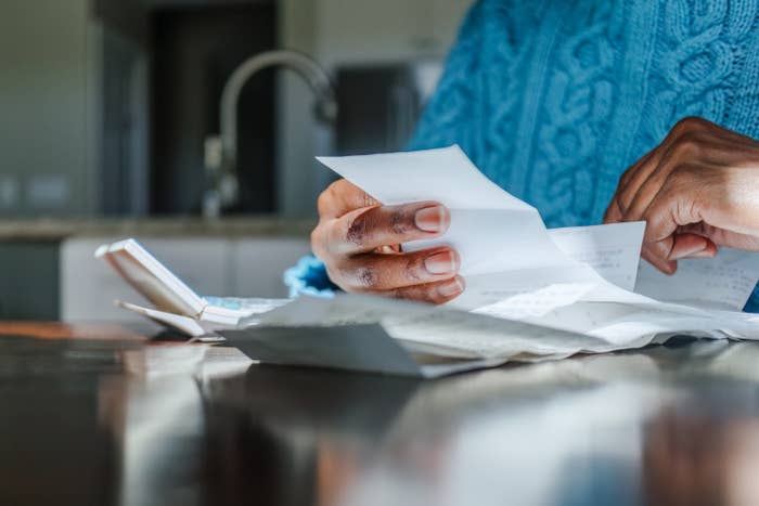 Person successful  a cozy sweater reviewing respective  receipts and documents astatine  a room  counter