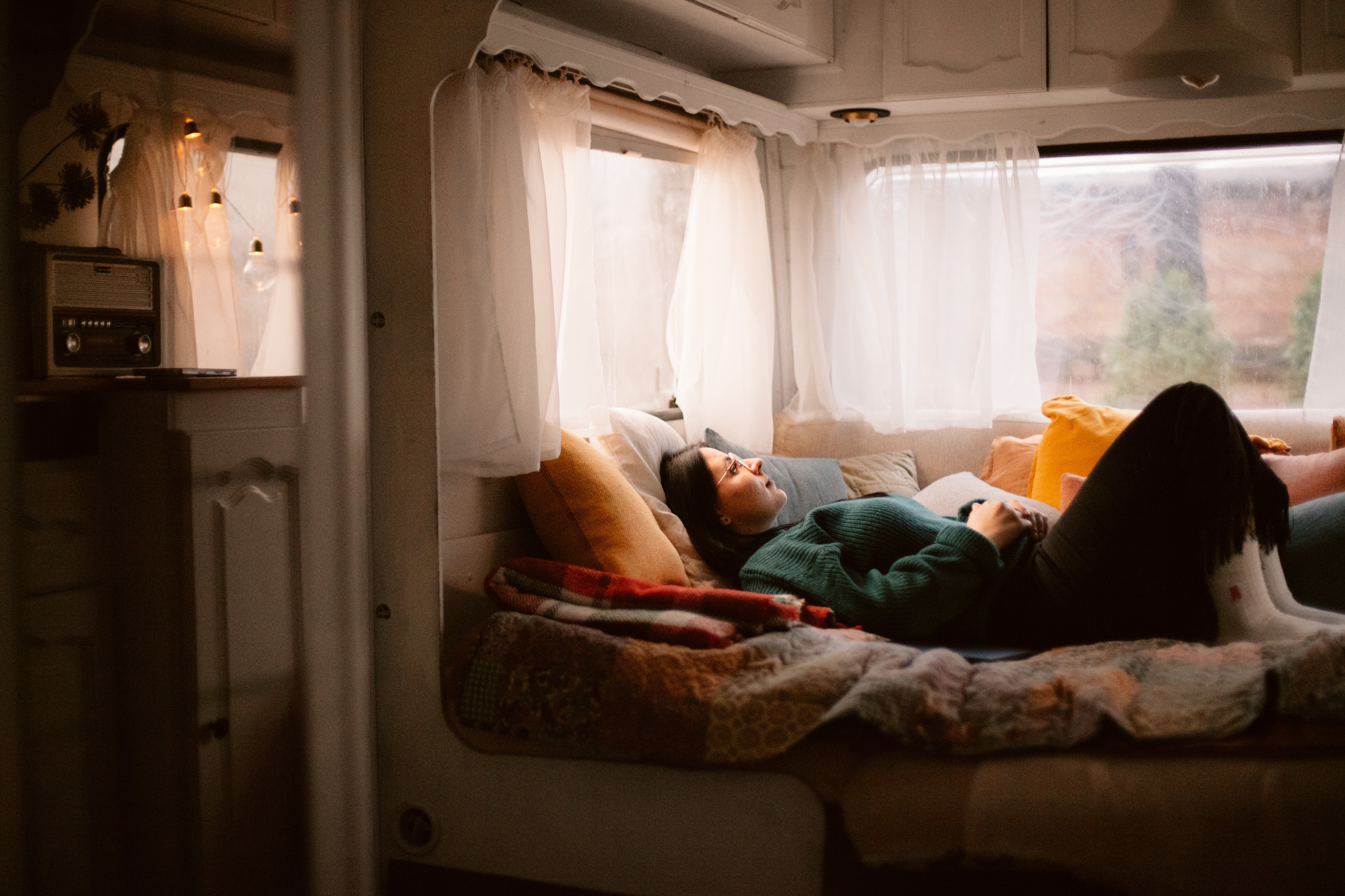 Person relaxing connected a furniture wrong a cozy camper, surrounded by pillows and brushed lighting, gazing retired of the window