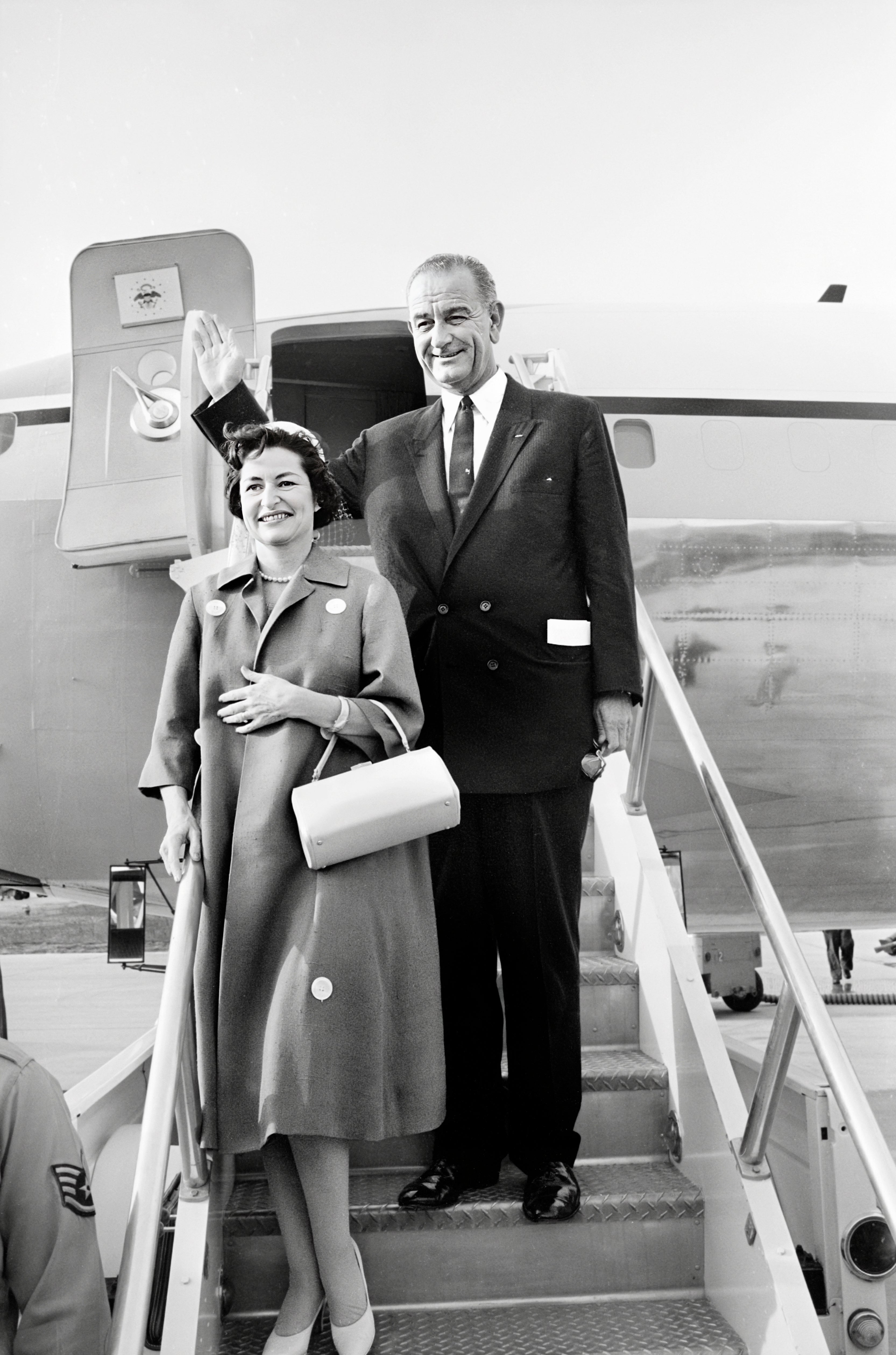 A mates waves from an airplane staircase. The antheral is successful a suit, and the pistillate is successful a overgarment with a handbag. They look to beryllium nationalist figures