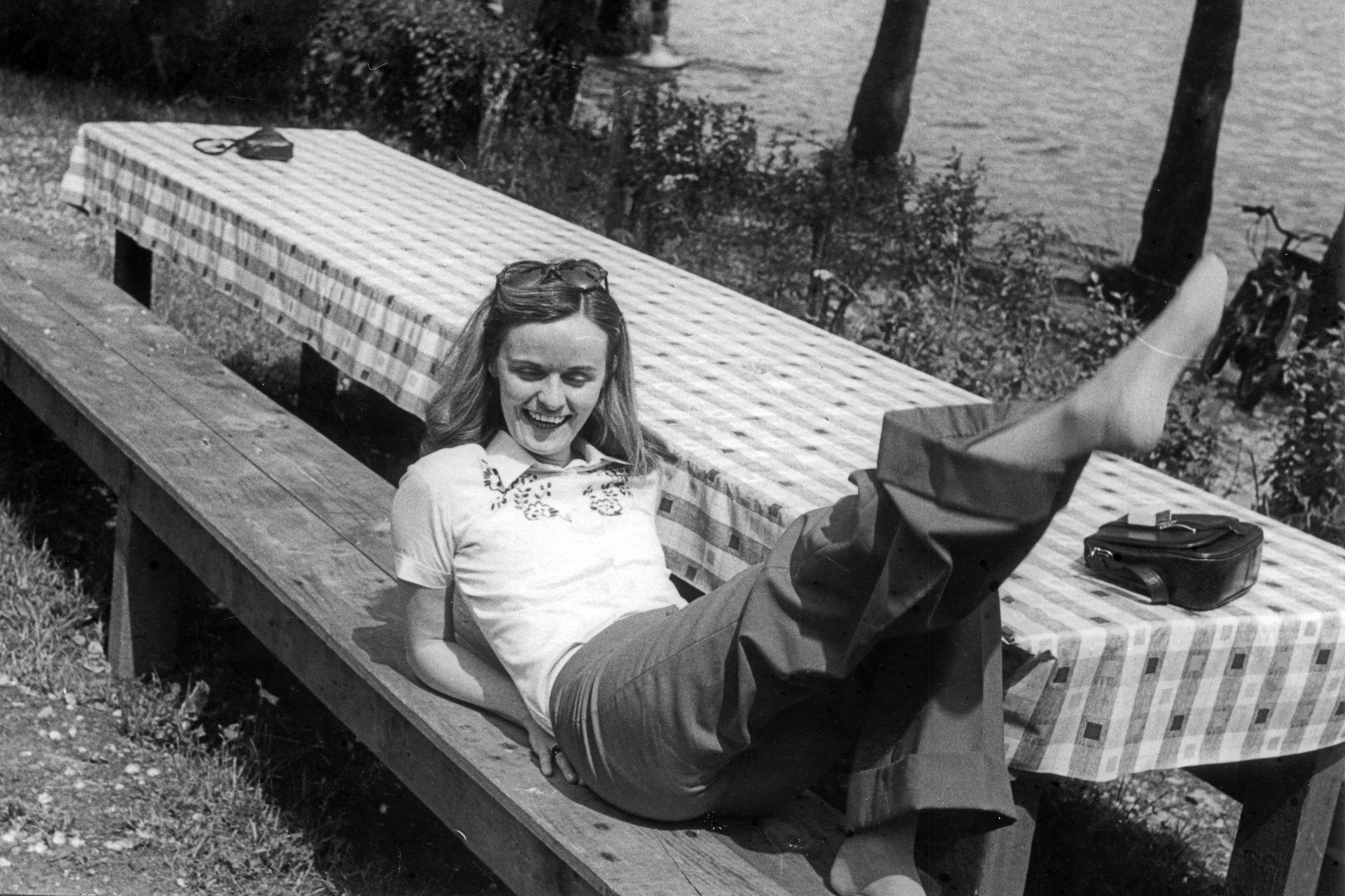 Woman relaxing connected  a picnic array  outdoors, smiling with 1  limb  playfully raised. Casual attire with a laid-back vibe