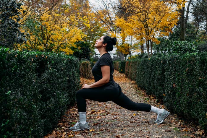 Person doing a lunge successful  a plot  pathway, surrounded by hedges and autumn trees