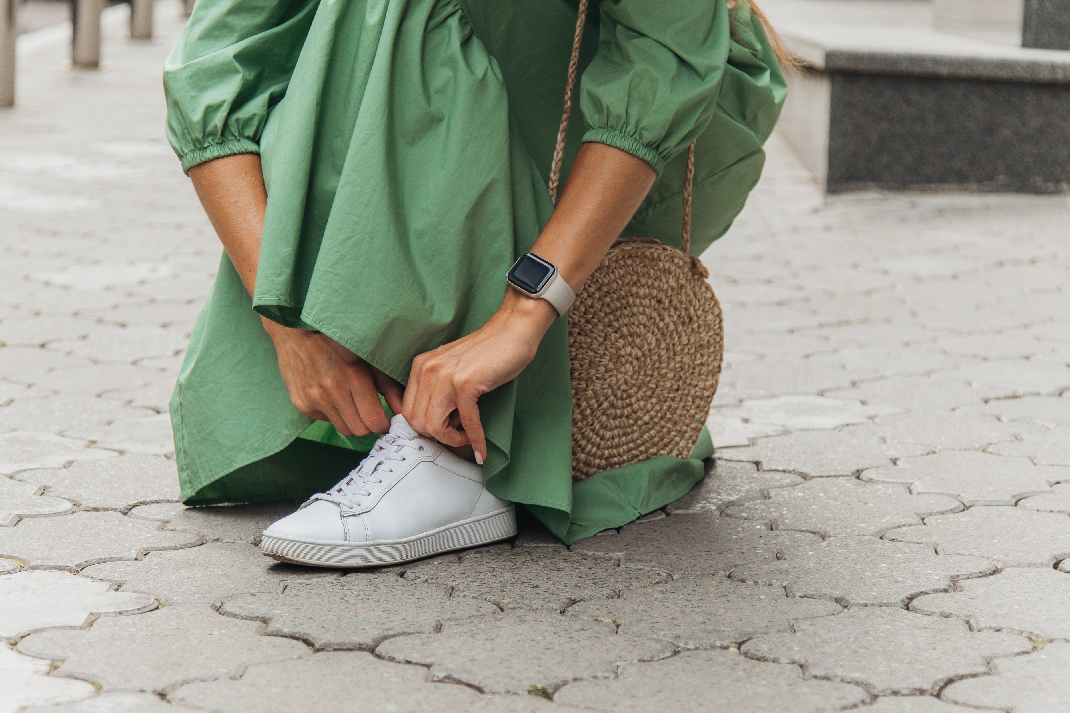 Person successful  a greenish  formal  crouched to necktie  achromatic  sneakers, wearing a circular  woven handbag and a smartwatch
