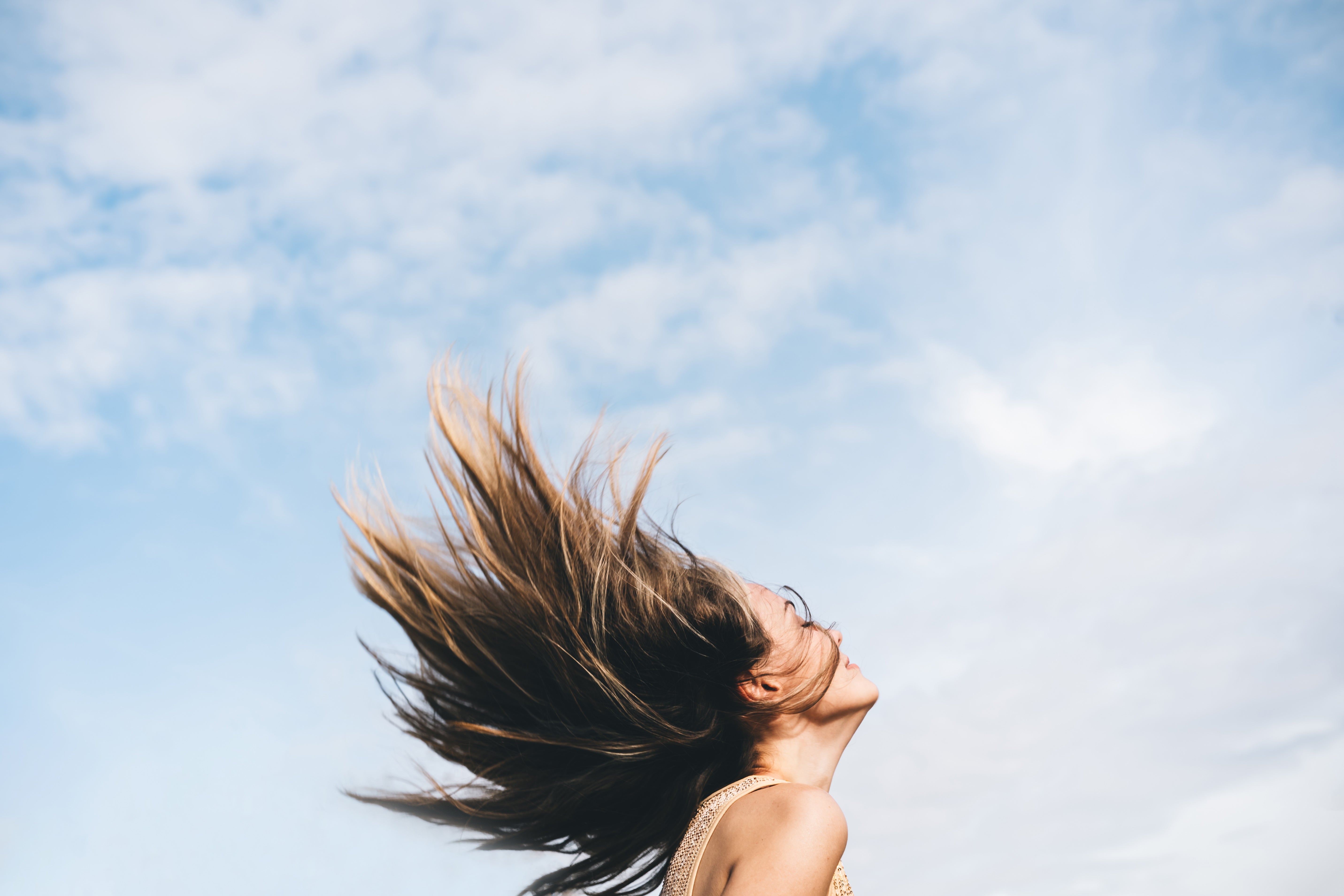 Person joyfully flipping hairsbreadth  backmost  against a cloudy entity  backdrop