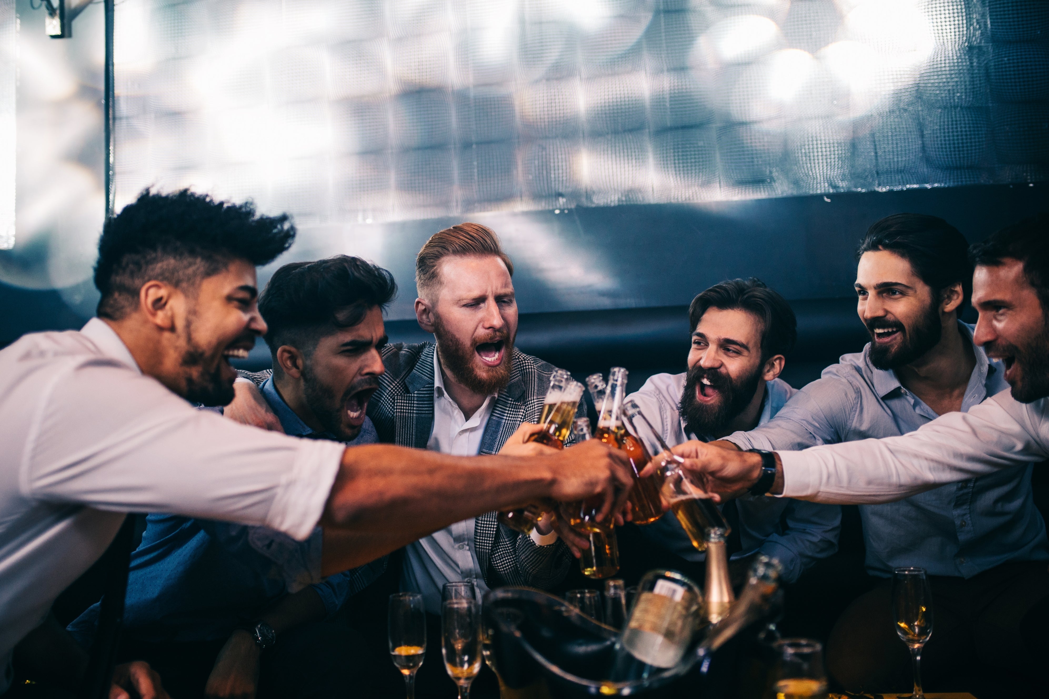 A radical of six men successful a lively barroom mounting clinking brew bottles and glasses successful a celebratory toast