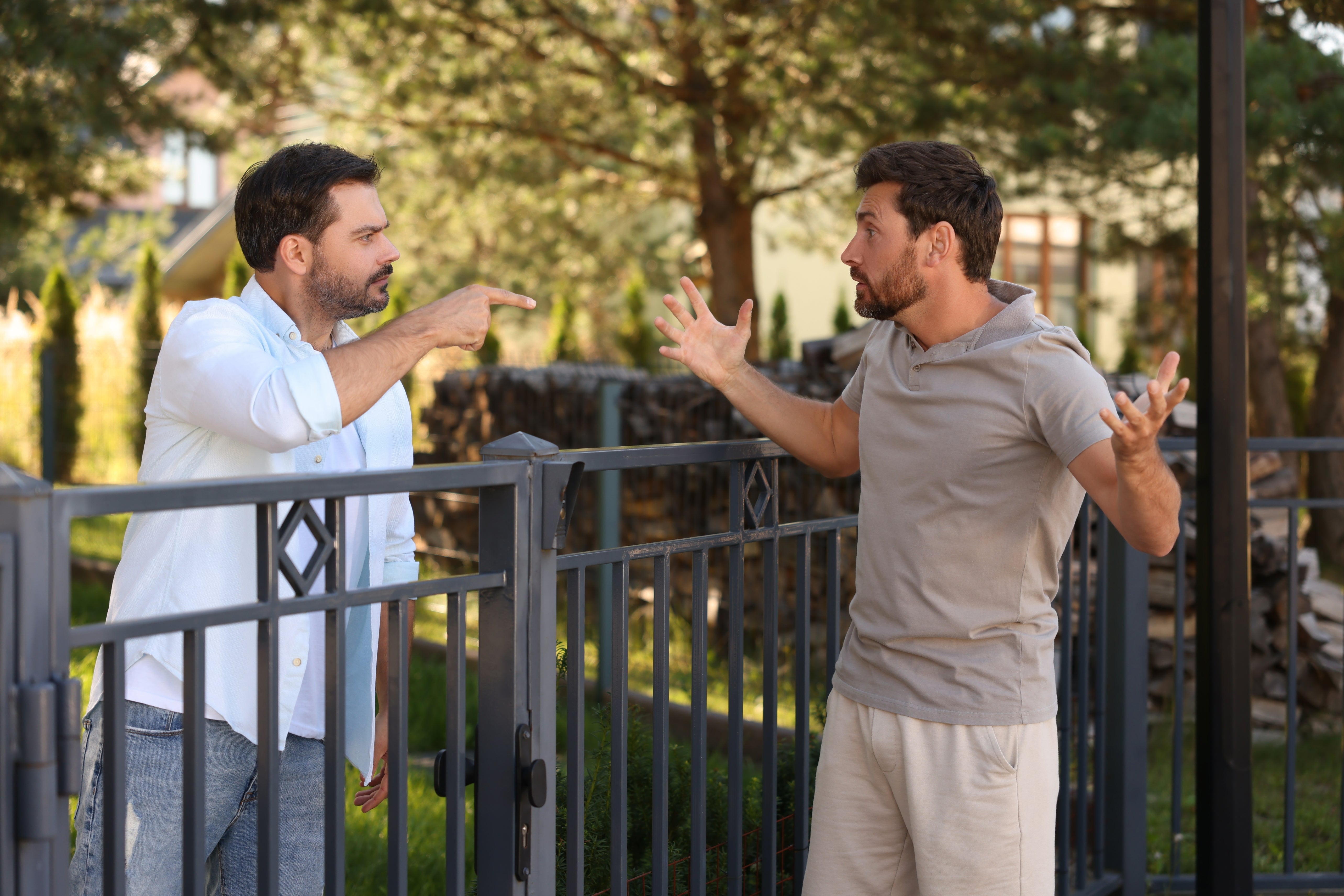 Two men having a heated treatment implicit a obstruction successful a residential area. One antheral points, portion the different gestures with unfastened arms