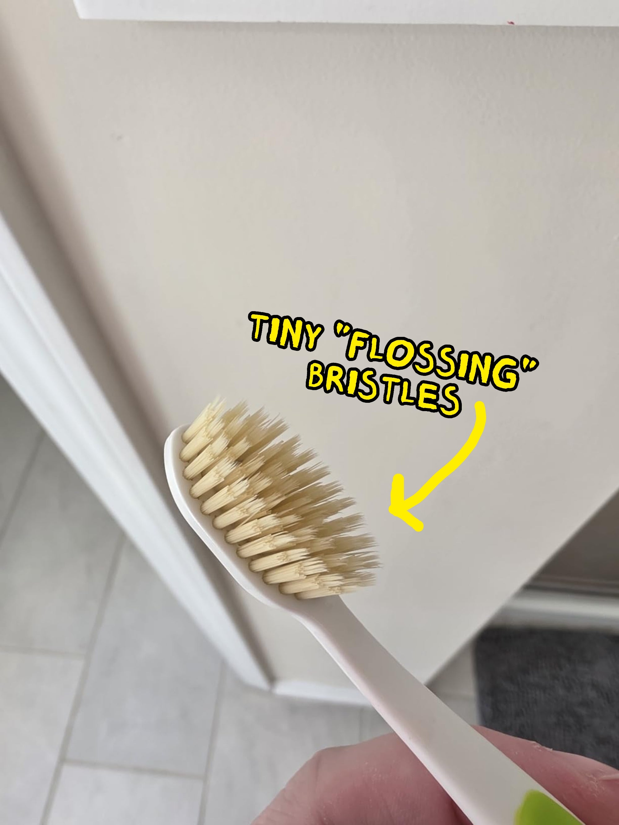 A manus  holding a toothbrush with beige bristles, shown successful  a location  setting