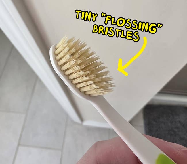 A manus holding a toothbrush with beige bristles, shown successful a location setting