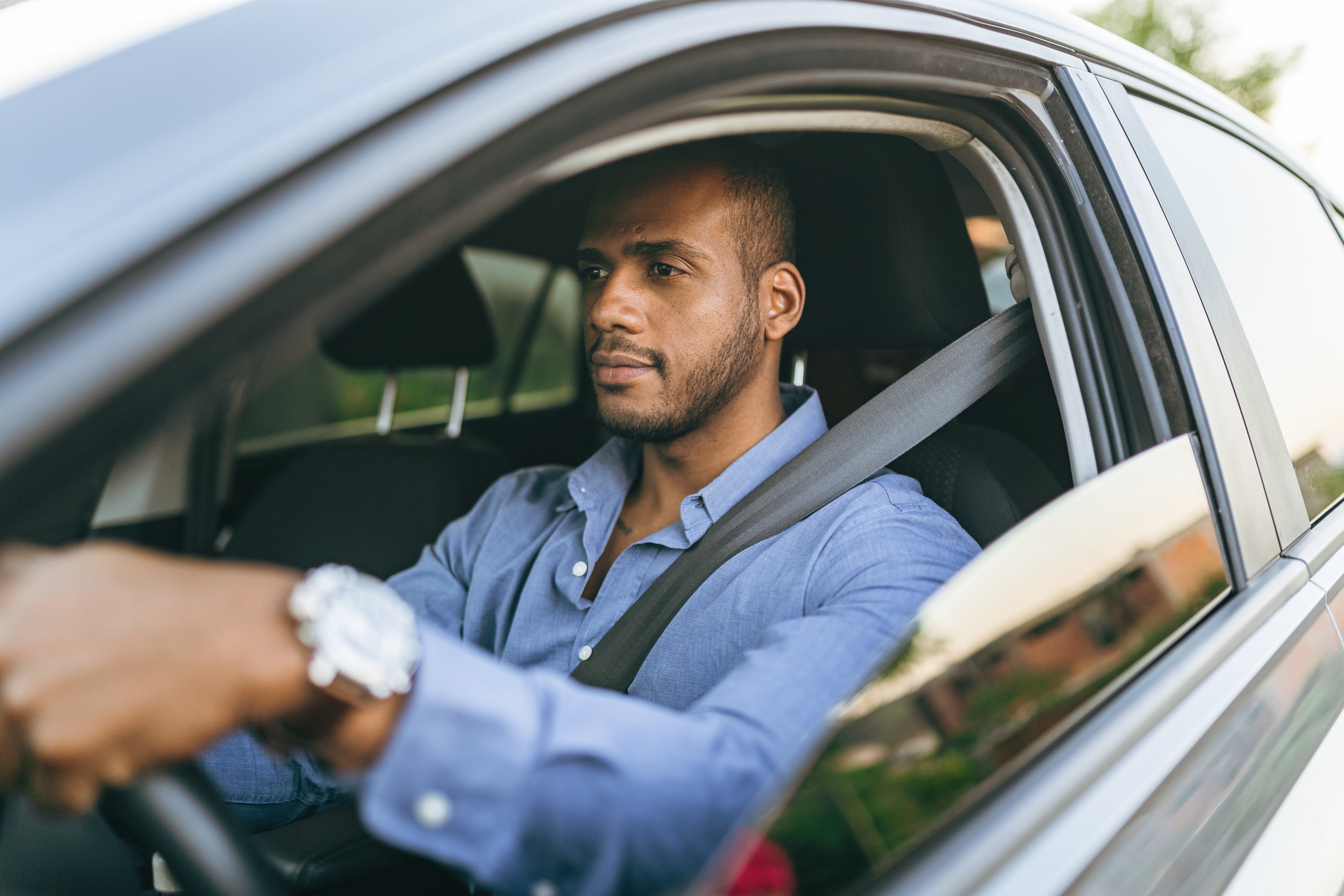 Person wearing a seatbelt, driving a car, looking focused