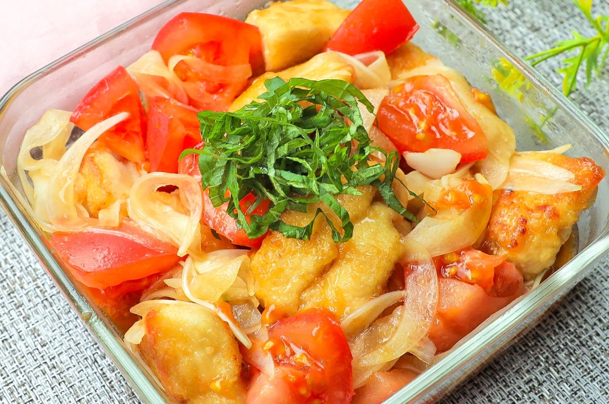 透明なガラス容器に、鶏肉とトマト、玉ねぎが盛られた料理。上に刻み青じそが乗っている。