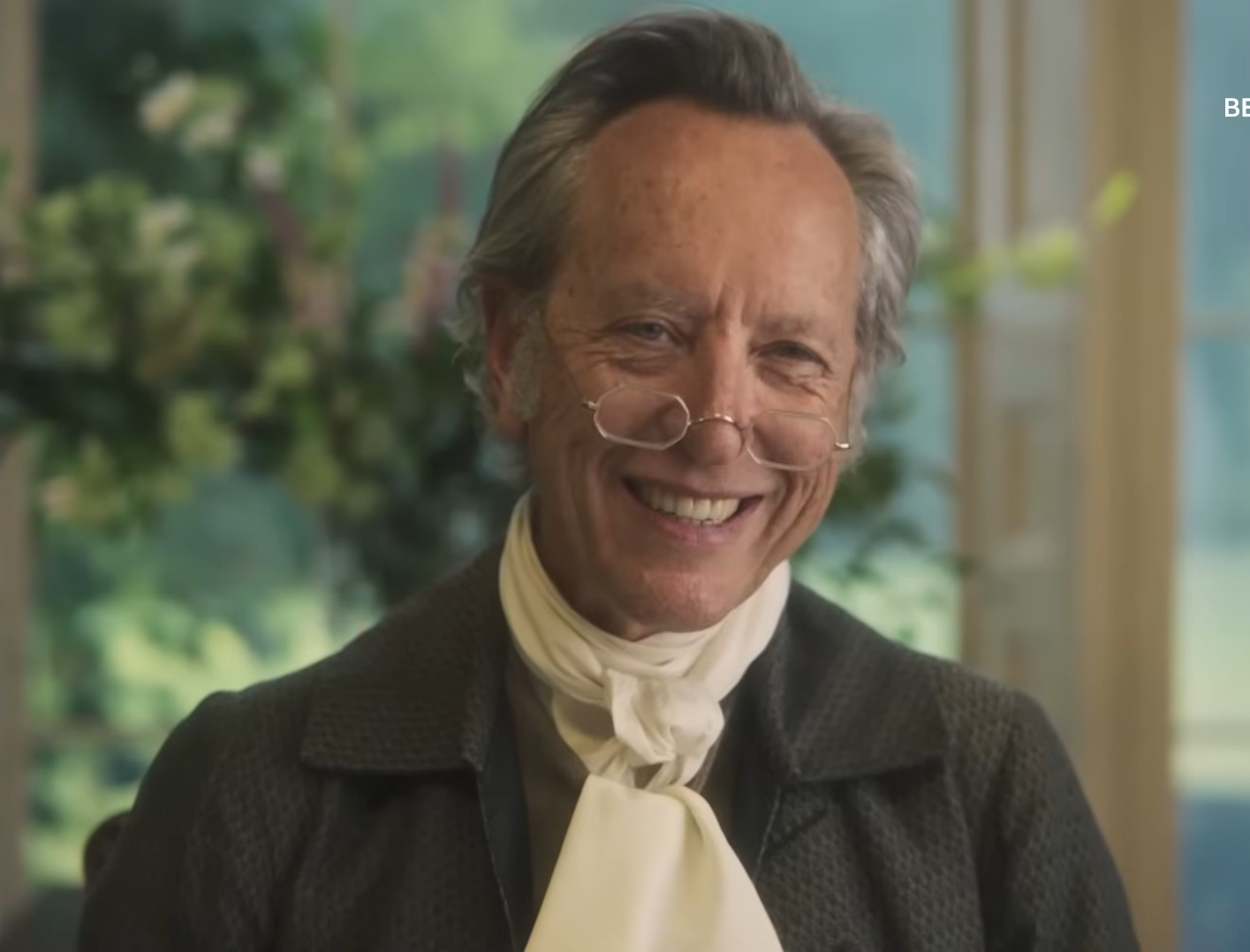 Smiling older man in period costume with glasses, indoors, in a scene from BBC's "The Other Bennet Sister."