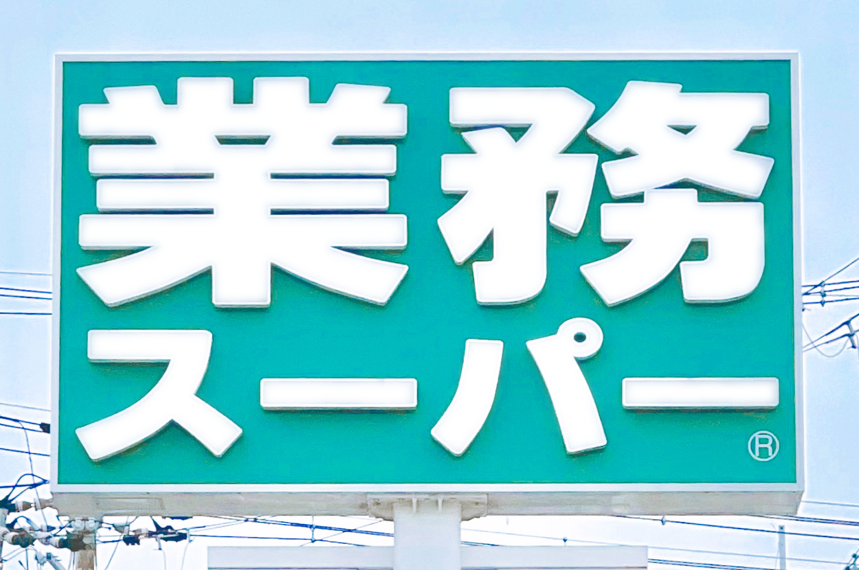 業務スーパーの看板。電柱と電線が背景に見える。