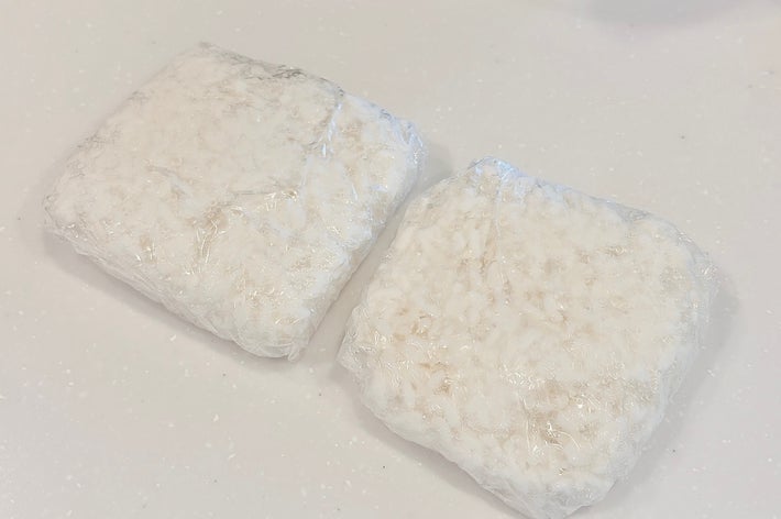 透明なラップで包まれた2つの四角い食品が白い台に置かれています。