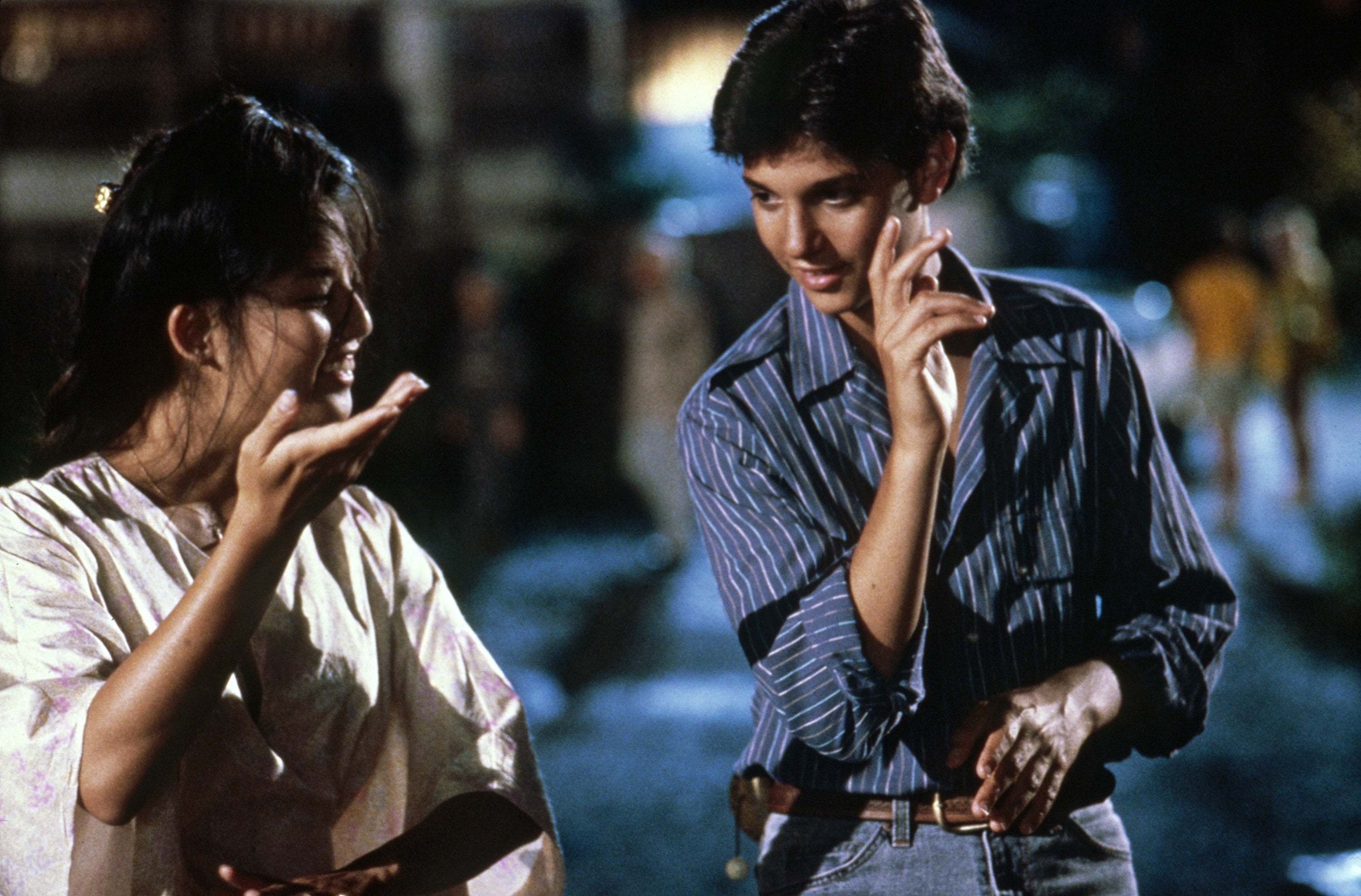 A young antheral   and pistillate   basal   outdoors astatine  night, gesturing expressively arsenic  if discussing thing  important, apt  successful  a movie  scene