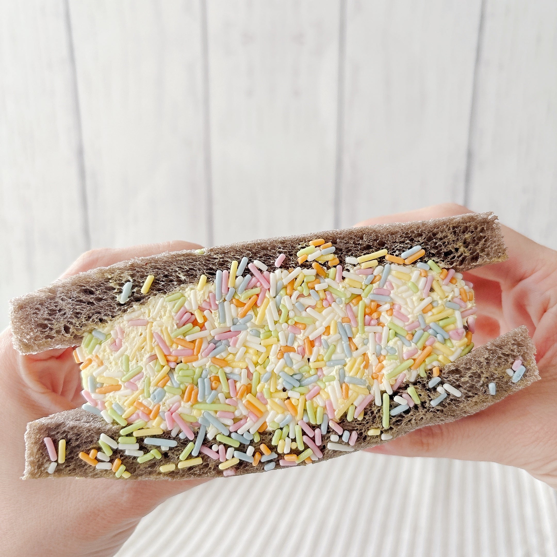 セブンｰイレブンの「よくばりサンド チョコバナナホイップ」両手で持ち上げている様子。