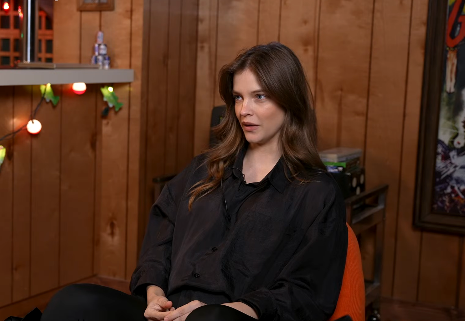Person sitting in a cozy room, wearing a casual, oversized black shirt, engaged in conversation