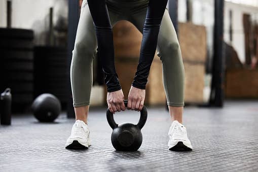 Person lifting a kettlebell successful  a gym, wearing leggings and sneakers, focusing connected  due  signifier  and technique