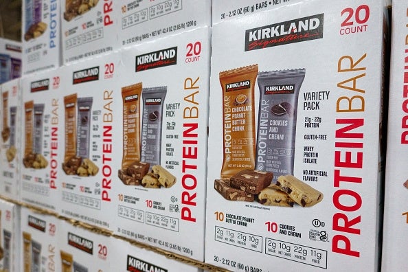 Boxes of Kirkland Signature macromolecule bars stacked connected shelves, featuring assortment battalion with flavors similar cocoa spot and cookies and cream