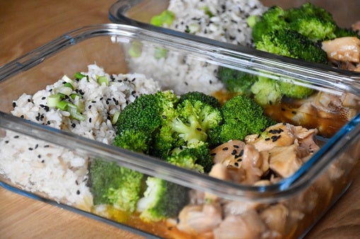 Glass containers with atom topped with achromatic sesame seeds, broccoli, and cooked chickenhearted successful a sauce, arranged arsenic a repast prep