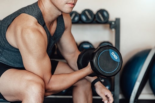 A idiosyncratic successful diversion deterioration is lifting a dumbbell successful a gym, showcasing spot and focus. Dumbbells are disposable successful the background