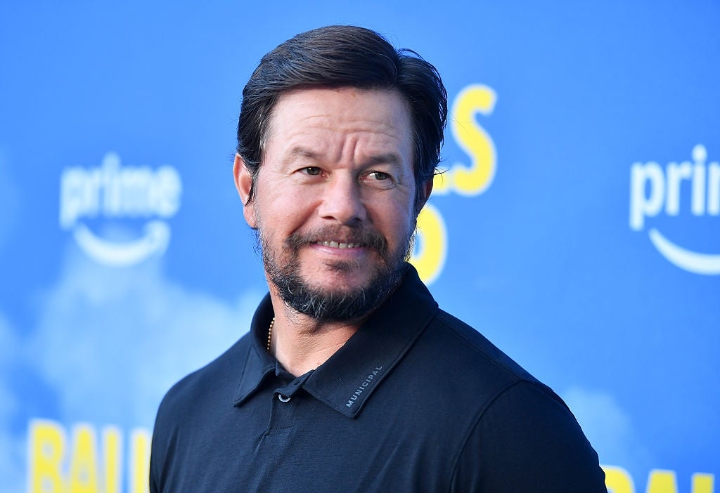 Mark Wahlberg, wearing a polo shirt, smiling, at an event