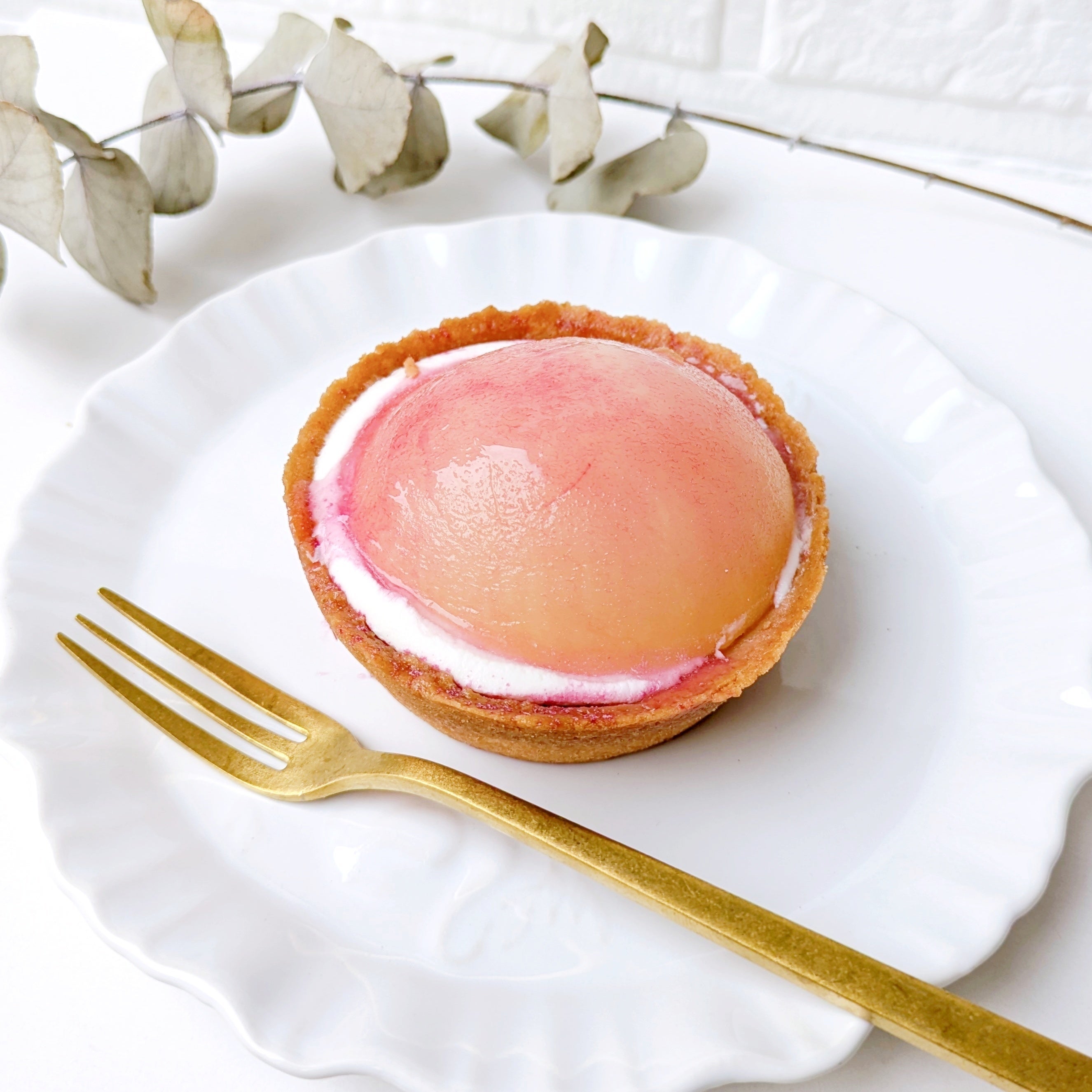 LAWSON（ローソン）の「ごろっと1/2個分！桃のタルト」白い皿に盛られた丸い桃タルト。