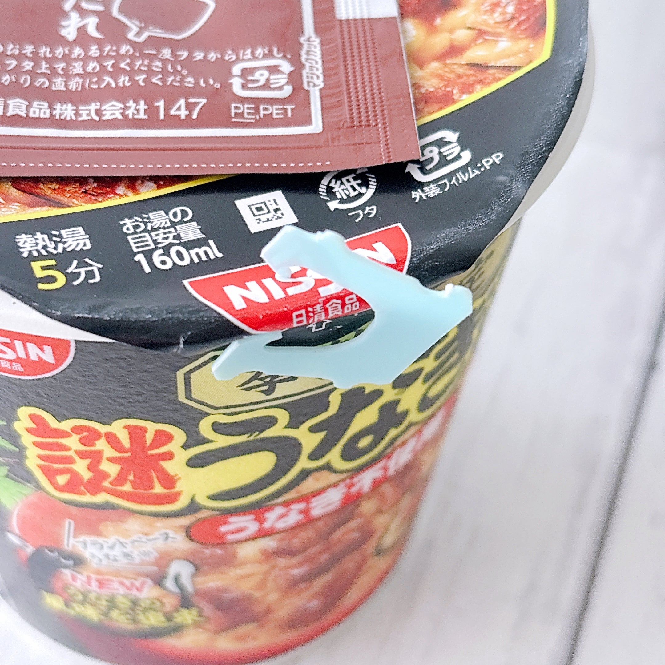 セブン‐イレブンで見つけた「日清謎うなぎ丼」フタをバッグクロージャーでとめている様子。