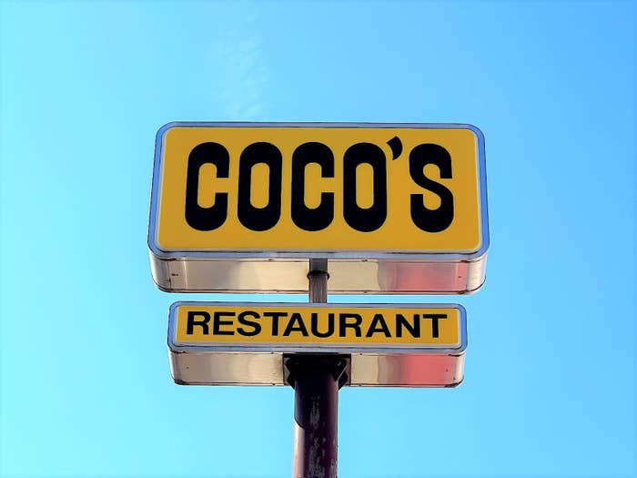 レストラン「COCO'S」の看板が青空を背景に写っている。