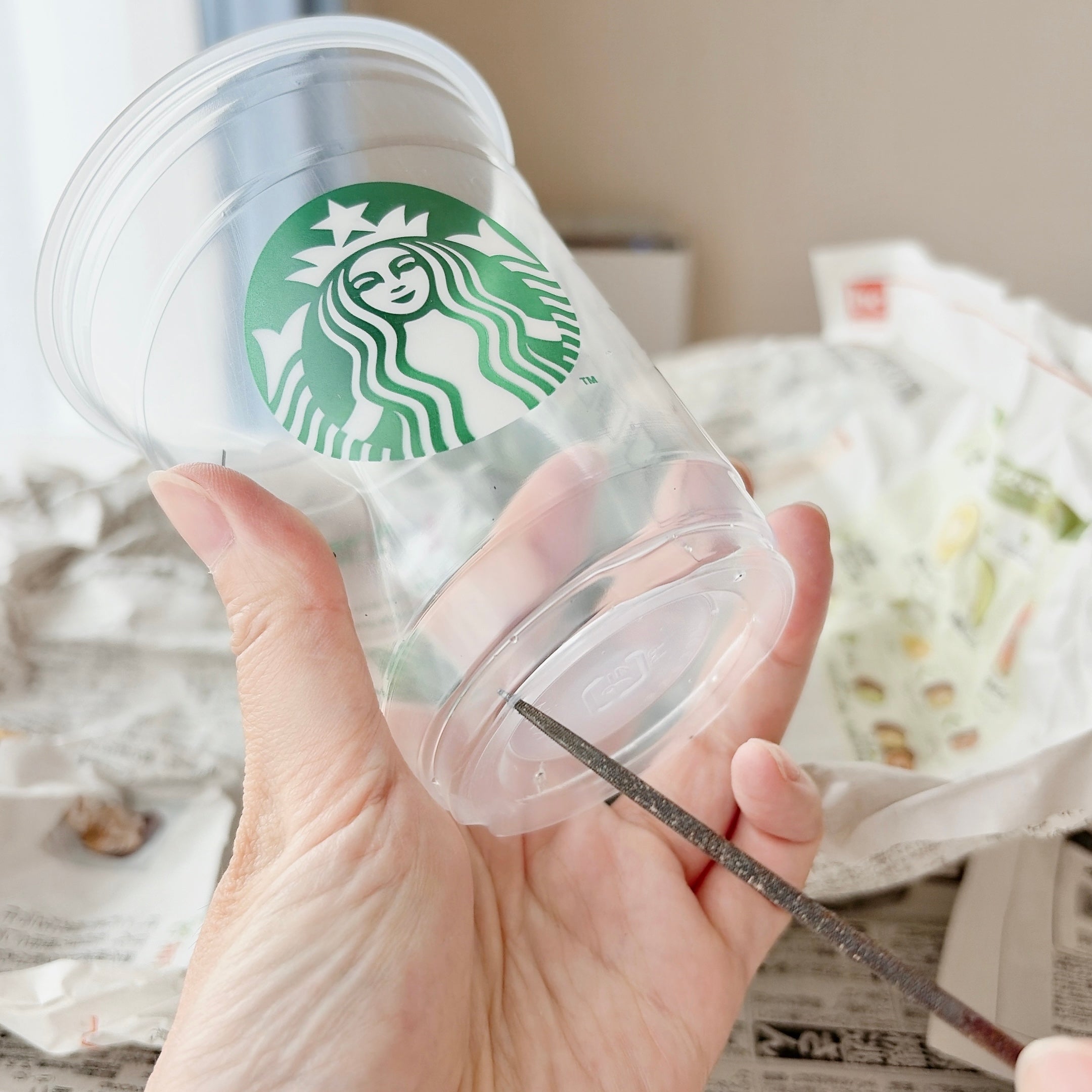 スターバックスのプラスチックカップに穴を開けている様子。