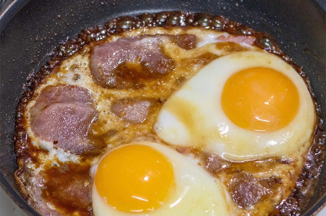 フライパンで焼かれているビーフパストラミと2つの目玉焼き。