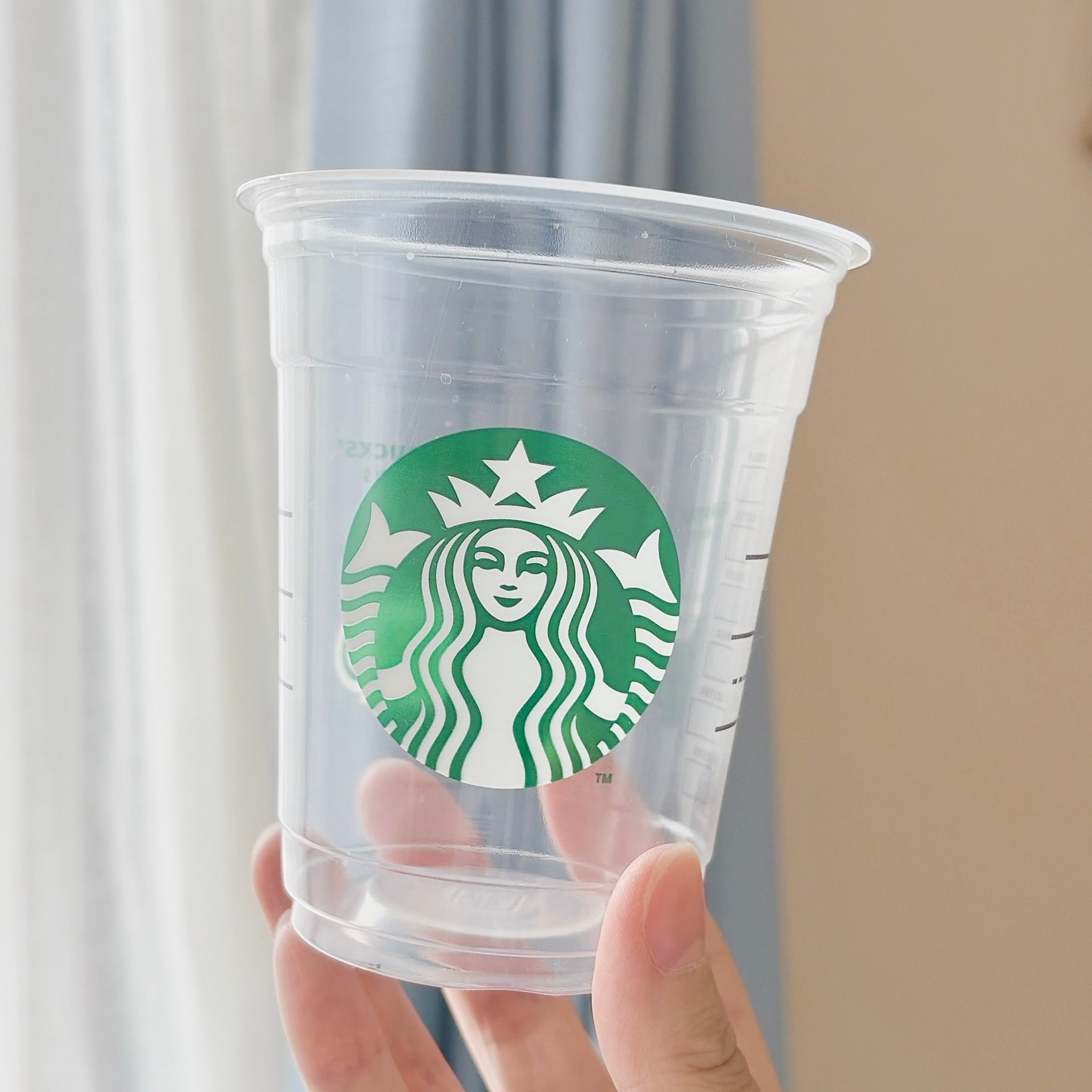 スターバックスの透明なプラスチックカップを持つ様子。