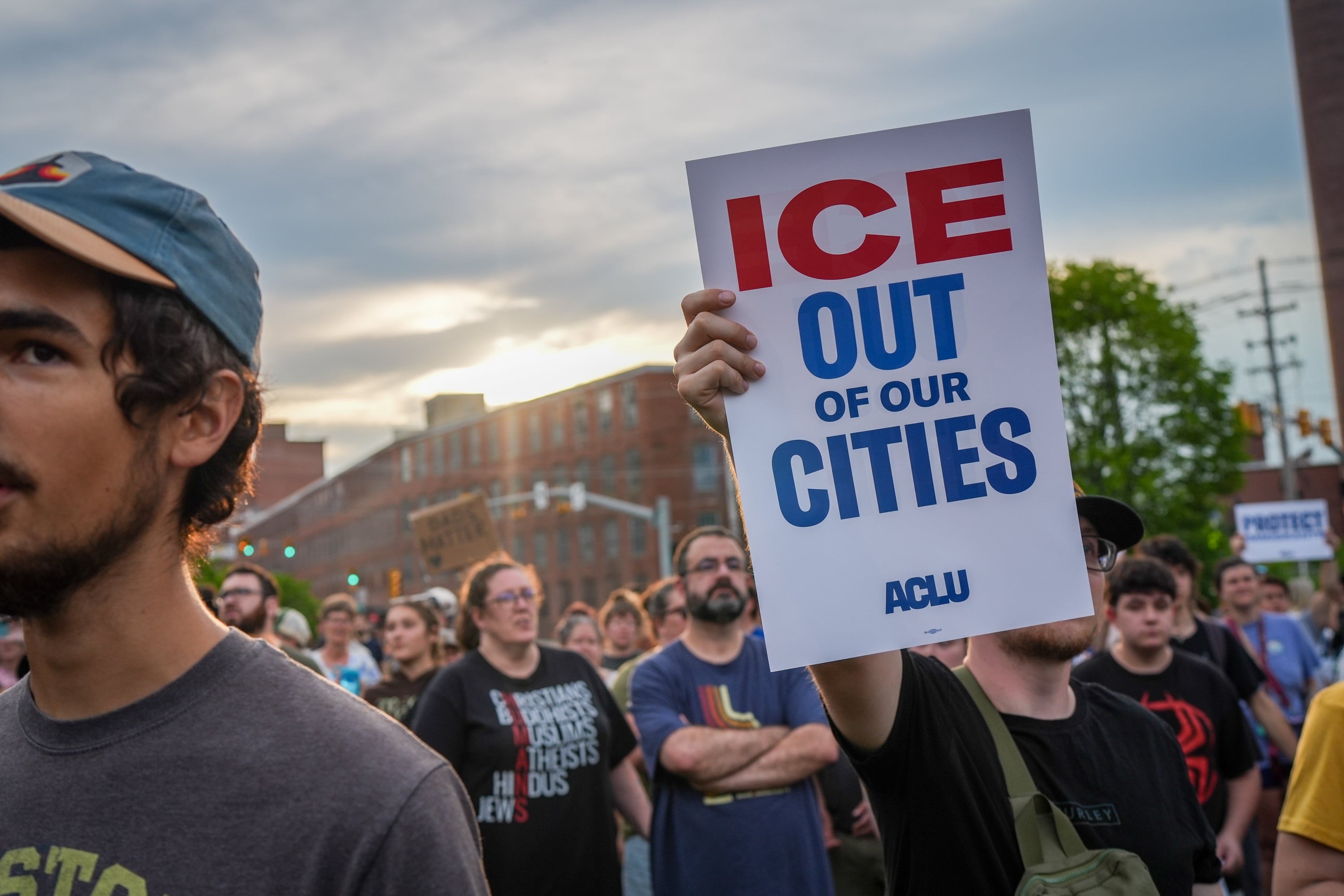 People astatine a rally; 1 holds a motion speechmaking "ICE Out of Our Cities" with ACLU branding