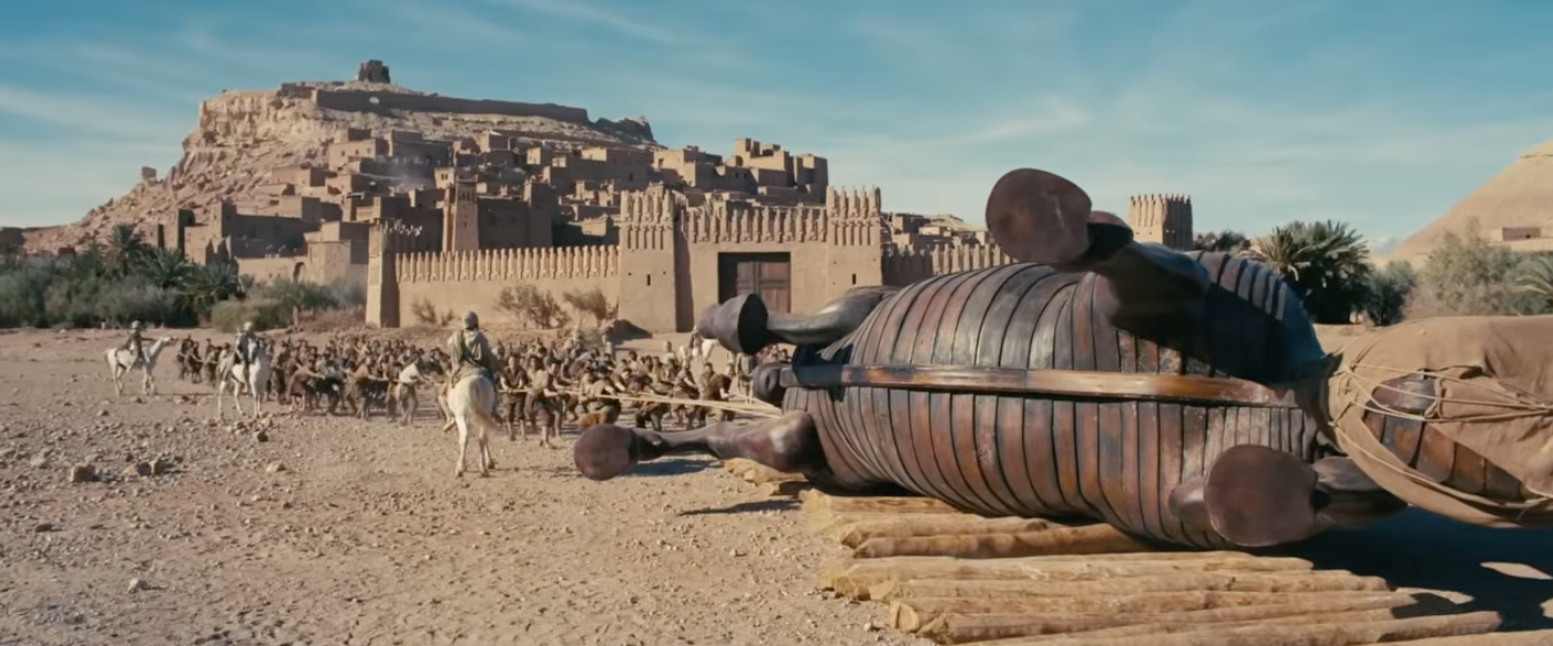 Scene from a historical film with a large wooden horse and soldiers outside an ancient fortress