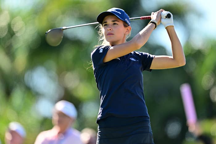 Person successful  play  attire with cap, mid-swing connected  a play  course, trees successful  background