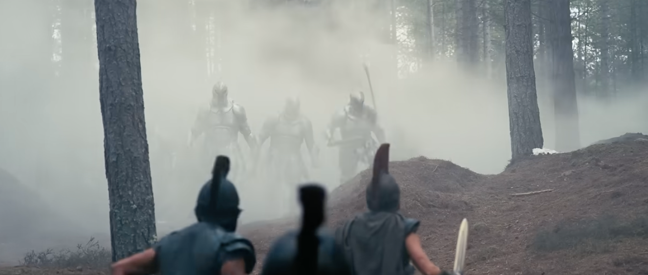 Two warriors in a forest confront advancing armored figures obscured by mist